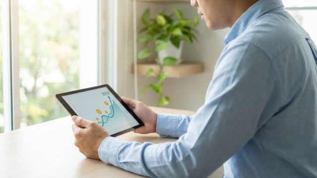 Homme consultant un graphique de croissance financière sur une tablette numérique.